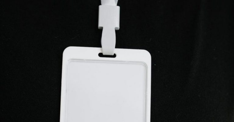 E-learning Security - Plastic name tag with white ribbon and blank paper hanging on black background