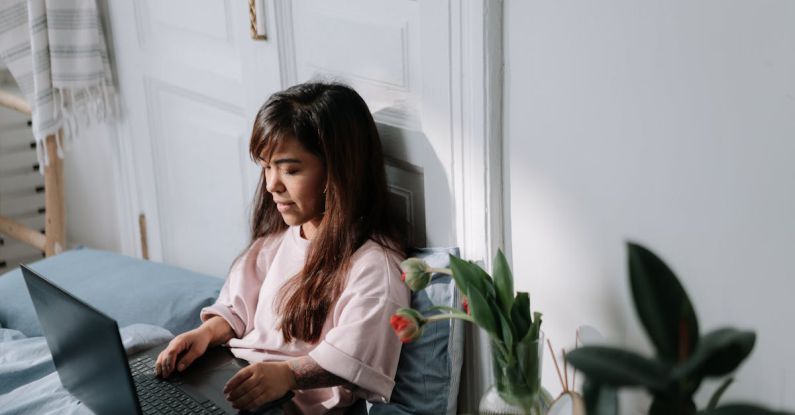Genetic Ethics - Dwarf girl sitting in bed and typing on laptop