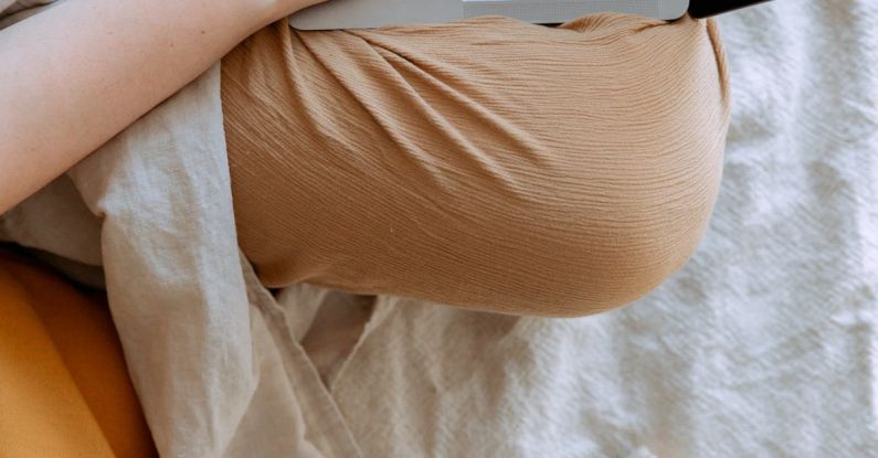 Big Data Education - Anonymous woman in casual clothes sitting on sofa and browsing laptop with blank screen while working on project on bed