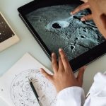 Data Healthcare - Crop African American student studying craters of moon on tablet at observatory